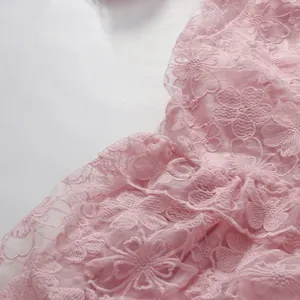 Detailed macro view of pink floral embroidered lace fabric texture for an elegant dress.