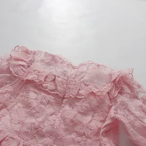 Detailed close-up of pink floral lace and ruffled neckline on an elegant vintage dress