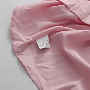 Close-up view of washing care label and 100% polyester fabric texture on pink dress
