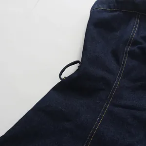Detailed view of dark blue denim fabric showing high-quality yellow stitching and texture