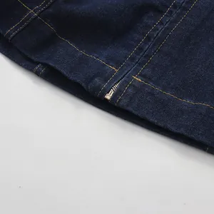 Close-up of metal zipper and contrast yellow stitching on dark blue denim fabric