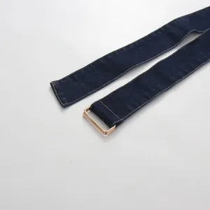 Detail of the dark blue denim belt with a gold-tone rectangular metal buckle