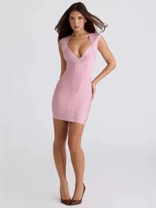 Full body view of a model wearing a pink V-neck bandage mini dress on neutral background