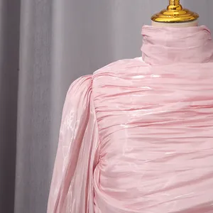 Primer plano detallado de la tela plisada rosa de un vestido elegante con cuello alto