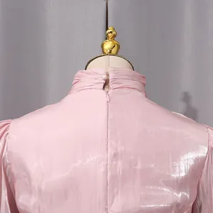 Vista detallada de cremallera y cuello alto en vestido rosa plisado elegante