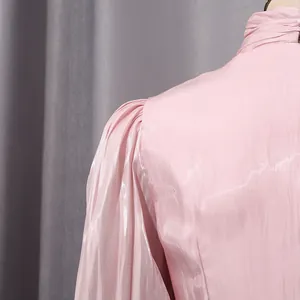 Primer plano del elegante hombro plisado y el tejido brillante de este vestido rosa