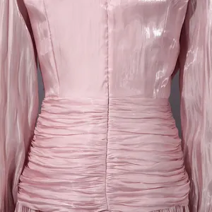 Detalle de la cintura plisada y la textura brillante de un vestido rosa de estilo francés.