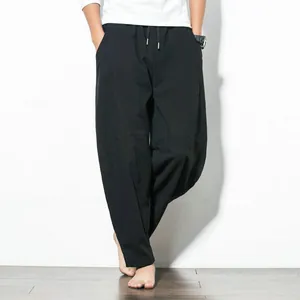 Detail view of men's loose black harem pants with drawstring waist and wide legs.