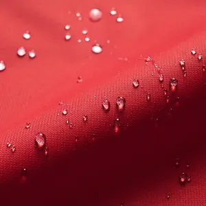 Detalle macro de tela roja impermeable con gotas de agua en chaqueta para exteriores