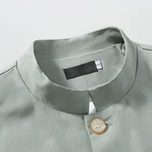Detail view of a men's sage green cotton linen jacket with a Mandarin collar and button