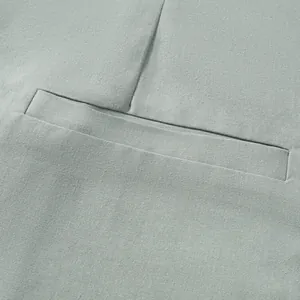 Detailed view of sage green cotton linen fabric and welt pocket on a men's blazer