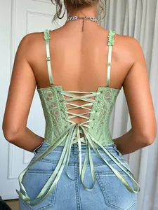 Dettaglio posteriore di un corsetto in pizzo verde chiaro con elegante lacci in raso.