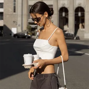 Vista dettagliata di un crop top a corsetto in raso bianco indossato in un ambiente urbano