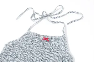 Dettaglio ravvicinato di abito a righe blu con scollo all'americana e fiocco rosso decorativo