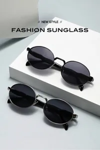 Detalle de gafas de sol ovaladas retro de metal en acabados negro y plateado de moda