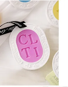 Close-up of a decorative purple and white plaster fragrance wax tablet with ribbon for home