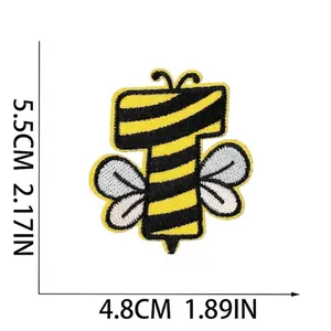 Detailed macro view of the bee-themed embroidered letter T patch with size markings