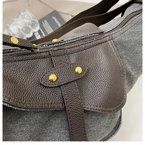 Macro view of gray canvas and brown leather bag showing gold rivets and texture