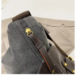 Close-up showing the durable gray canvas texture and leather zipper pull of the bag.