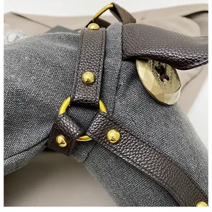 Close-up of textured canvas and leather strap with gold hardware on donkey bag