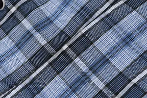 Macro detail of blue and black plaid denim fabric texture with woven checkered patterns
