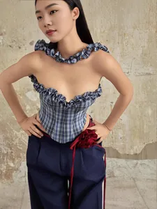 Stylish blue plaid corset top with ruffles paired with navy trousers and red flower