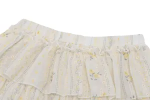Détail d'une mini-jupe blanche à volants avec un délicat motif floral jaune pastel
