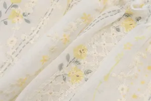 Détail de la broderie florale jaune et de l'imprimé sur un tissu de robe d'été blanc