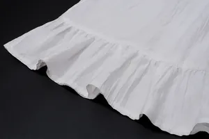 Zoom sur l'ourlet à volants blanc d'une jupe longue de style français avec texture.