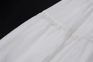 Gros plan sur la texture du tissu plissé blanc et la dentelle délicate d'une jupe longue