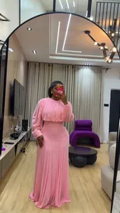 Dettaglio del set con camicia rosa a maniche a sbuffo e gonna lunga a vita alta sul modello.
