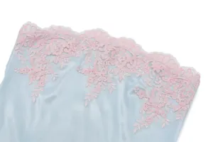 Vista macro detallada del elegante encaje floral rosa en el top tipo bustier de satén azul