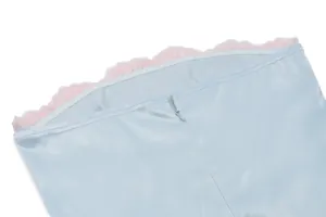 Detalle de top de satén azul claro con ribete de encaje rosa y cremallera invisible.