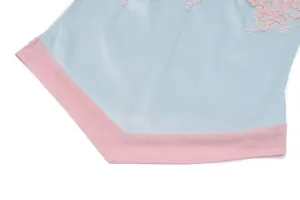 Primer plano de top satinado azul claro con encaje rosa y dobladillo de malla