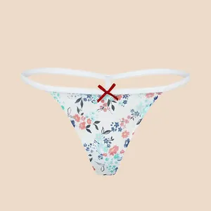 Weißer T-String mit Blumenmuster und roter Schleife auf einfarbigem Hintergrund