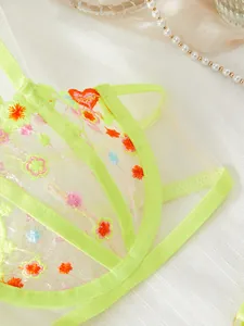 Détail d'un soutien-gorge en maille vert fluo avec de délicates broderies florales