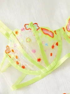Détail de lingerie en maille vert fluo avec broderie florale et texture transparente