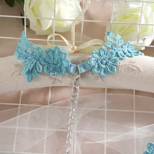 Gros plan d'une jarretière en dentelle bleue à motifs floraux et chaîne argentée