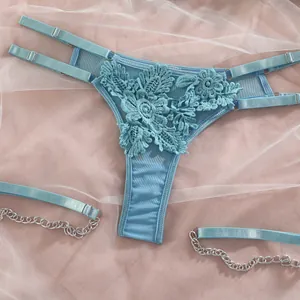 Gros plan d'un string en dentelle bleue et d'anneaux de jambe avec chaînes en argent