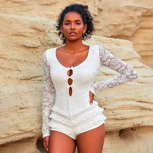 Detailed shot of a model wearing a white lace long-sleeved romper with cutouts and bows