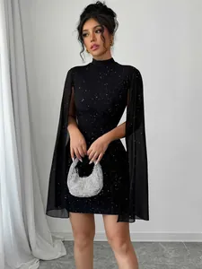 Détail d'une robe moulante noire à paillettes avec des manches cape élégantes