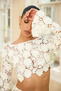 Detail shot of white floral lace long-sleeve crop top with delicate cutout pattern