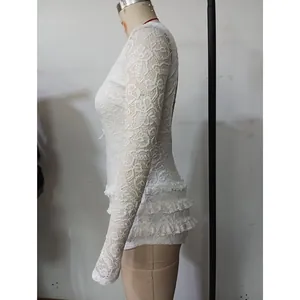 Side view of white long-sleeved lace romper with ruffle hem and delicate floral patterns