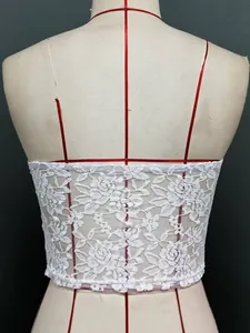 Détail rapproché du motif complexe de dentelle florale blanche sur un haut bustier.