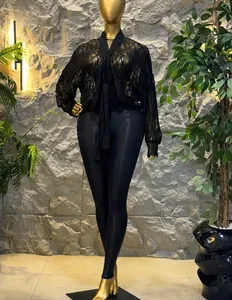 Élégant chemisier noir en dentelle transparente à manches longues sur mannequin doré