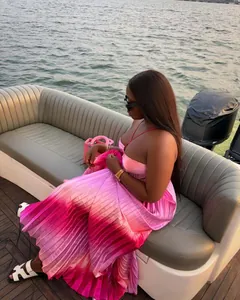 Detail of a pink ombre pleated maxi dress with spaghetti straps in a yacht setting.