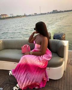 Elegant pink ombre pleated maxi dress with spaghetti straps shown on a yacht
