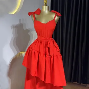 Détail d'une robe midi rouge avec bretelles à nœuds et ourlet à volants asymétrique.