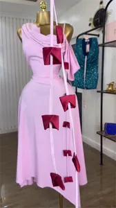 Detailed view of a pink one-shoulder midi dress featuring unique red fabric strap accents.