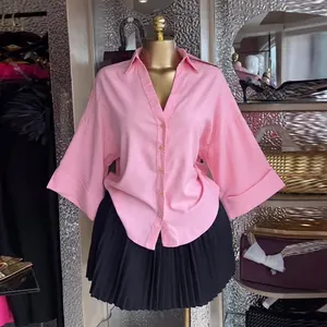 Dettaglio di una camicia rosa con maniche a pipistrello, colletto a revers e bottoni frontali